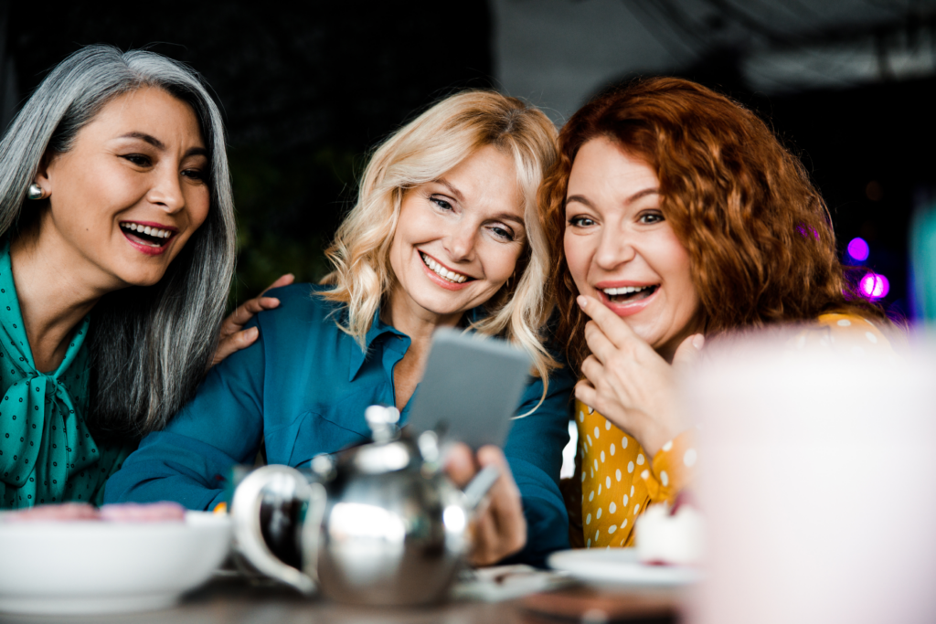 three women are laughing while having tea