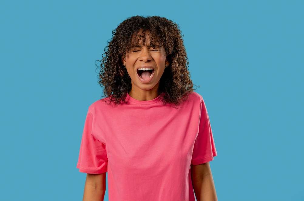 Woman in a pink shirt shouting in frustration, expressing perimenopause rage